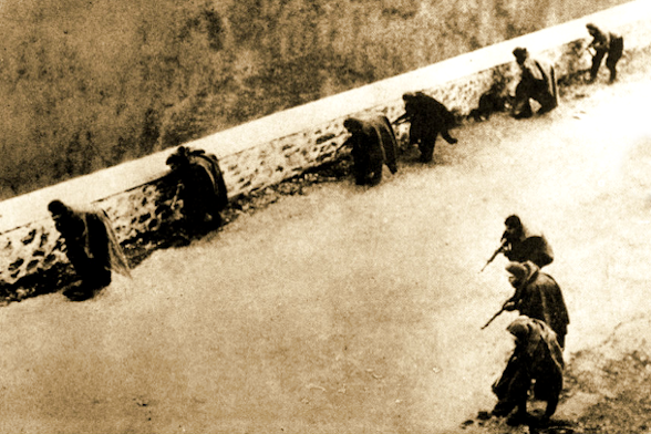 foto en blanco y negro en la que se ve dos hileras paralelas de combatientes medio agachados y provistos de armas